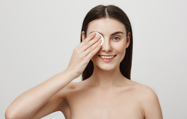 Настоящая голубоглазая девушка снимает макияж с лица