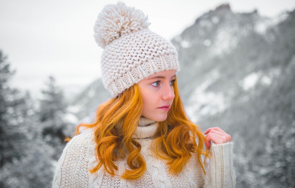 Рыжеволосая девушка в теплой шапке зимой 