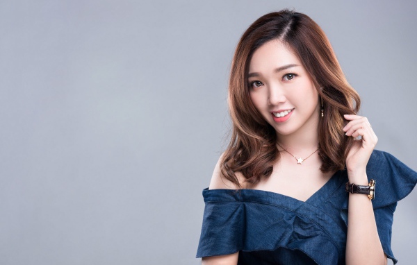 Улыбающаяся девушка азиатка с часами на руке на сером фоне