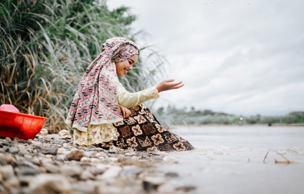 Улыбающаяся девушка азиатка сидит у воды