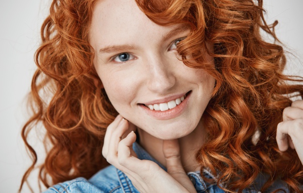 Улыбающаяся голубоглазая рыжеволосая девушка в джинсовой куртке 