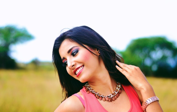 Улыбающаяся темноволосая девушка с украшением на шее 