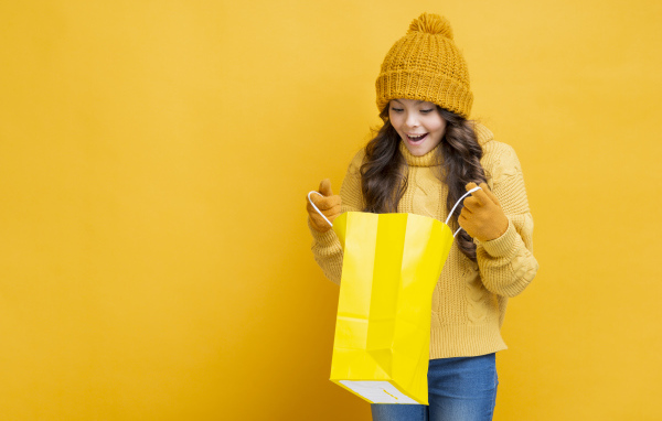 Улыбающаяся девушка в теплом свитере  с пакетом в руках 