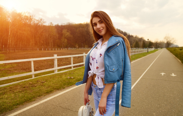 Smiling girl in blue leather jacket on the road