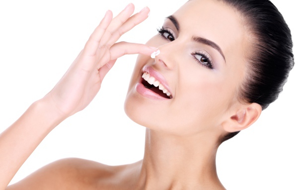 Улыбающаяся девушка мажет крем на нос 