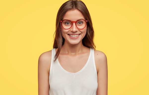 Улыбающаяся девушка в очках на желтом фоне 