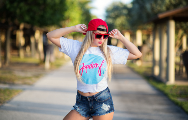 Стильная девушка в красной кепке и джинсовых шортах 