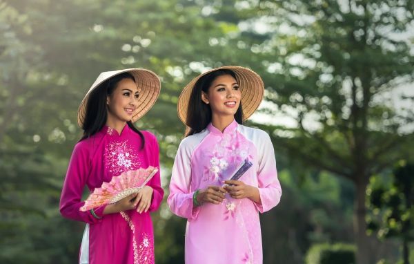 Две девушки азиатки в платьях с веером в руках