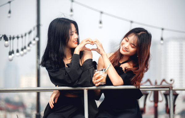 Две девушки азиатки делают сердце руками 