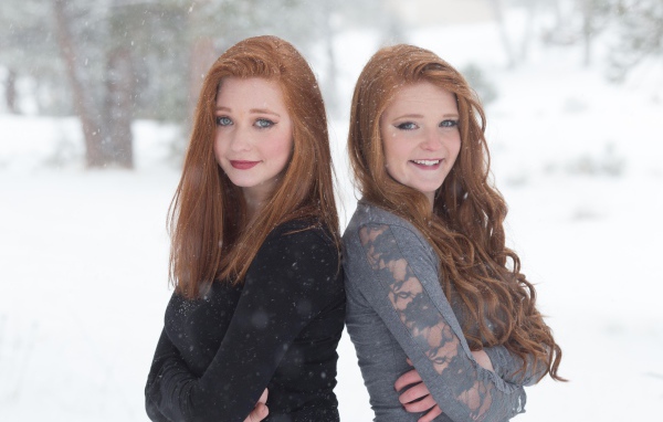 Две улыбающиеся рыжеволосые сестры на улице зимой 