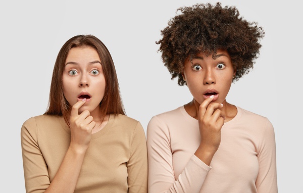 Две удивленные девушки на сером фоне 