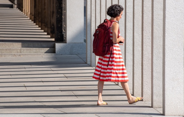 Женщина в красном полосатом платье с рюкзаком