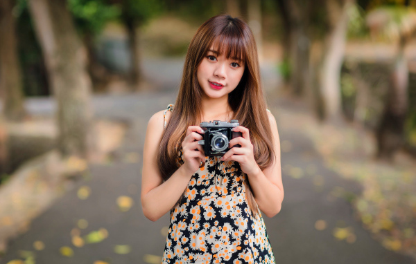 Молодая девушка азиатка с фотоаппаратом в руках 