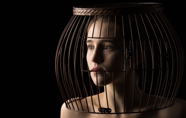 Молодая девушка с клеткой на голове 