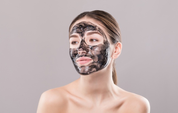 Молодая девушка с косметической черной маской на лице