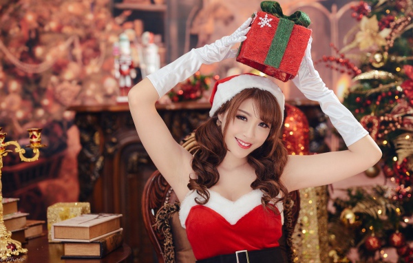 Красивая девушка азиатка в костюме Снегурочки с подарками