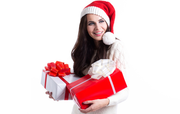 Улыбающаяся девушка в новогодней шапке с подарками на белом фоне