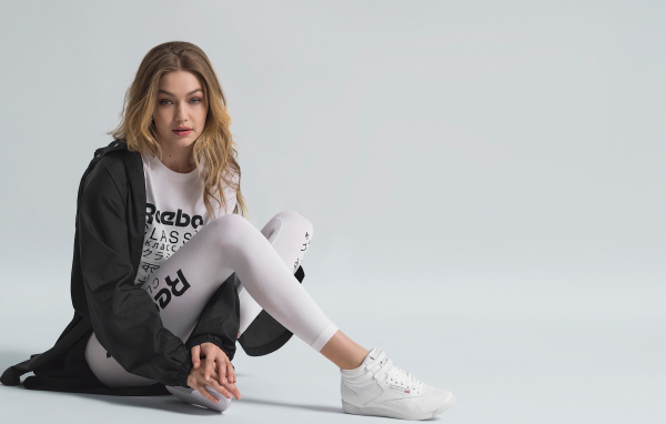 American supermodel Gigi Hadid in a tracksuit sits on the floor