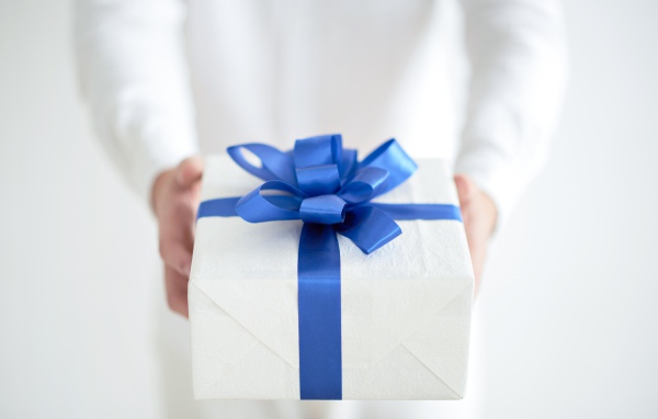Подарок с голубым бантом в руках 