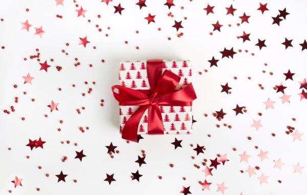 Подарок с красным бантом на белом фоне со звездочками