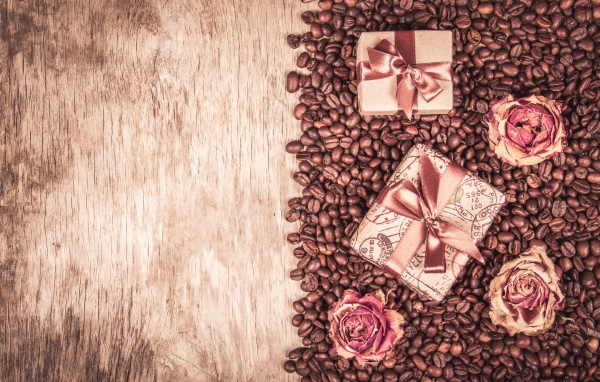 Подарки и розы лежат на кофейных зернах