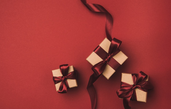 Три подарочные коробки с бантами на красном фоне