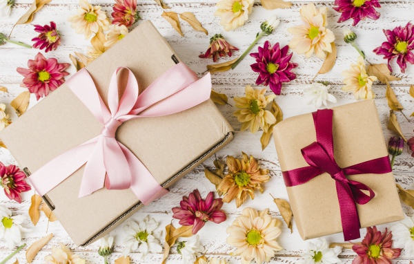 Two boxes with gifts on a table with chrysanthemum flowers