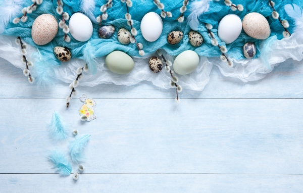 Яйца на ткани с ветками вербы на столе