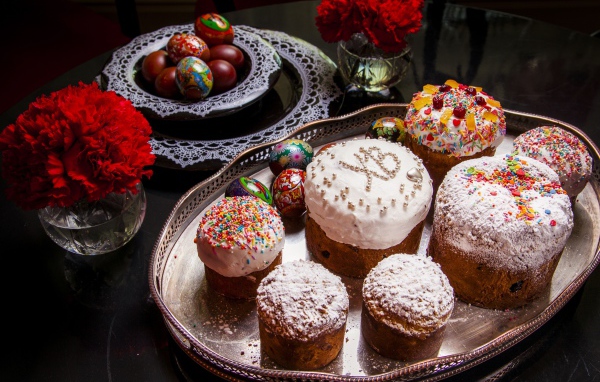 Много куличей на столе с гвоздиками и крашеными яйцами на праздник Пасха