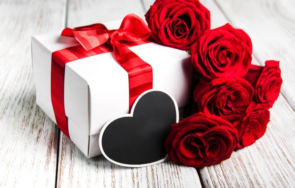 Букет красивых красных роз на столе с подарком для любимой на 8 марта