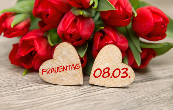 Два сердечка на столе с букетом красных тюльпанов на 8 марта 