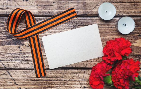 Красные гвоздики, георгиевская лента и свечи на столе, шаблон для открытки на 9 мая День победы