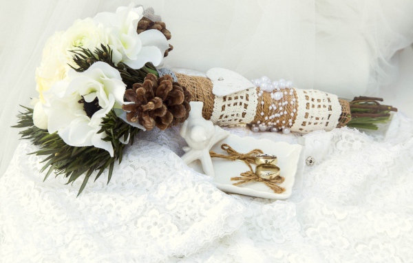 Букет невесты из цветом анемоны лежит на платье с обручальными кольцами