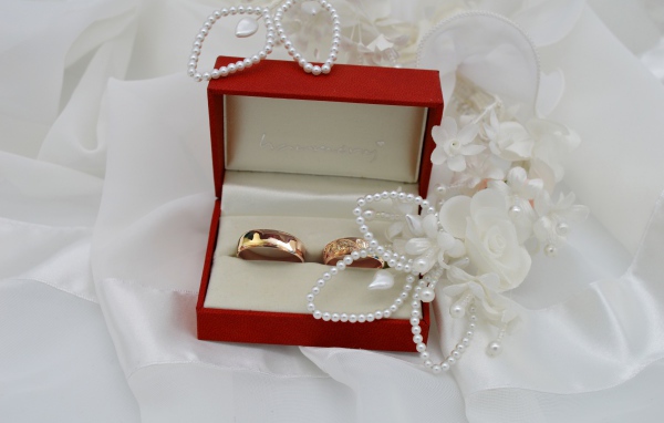Золотые обручальные кольца в красной коробочке с украшениями