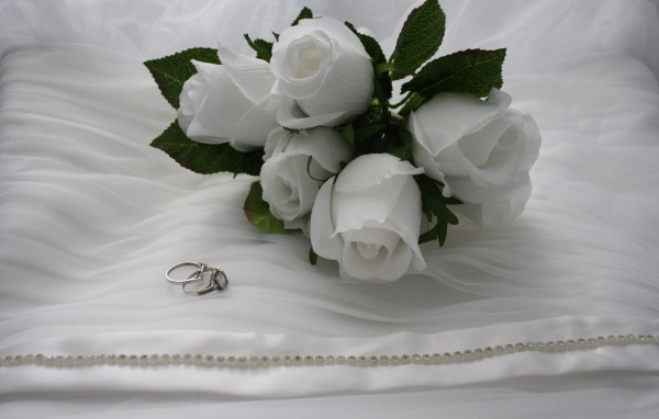 Белые бутоньерки с кольцами на белом покрывале 