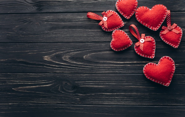 Много красных сердечек из фетра на деревянном столе