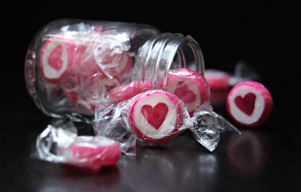 Конфеты с сердцем в стеклянной банке на черном фоне