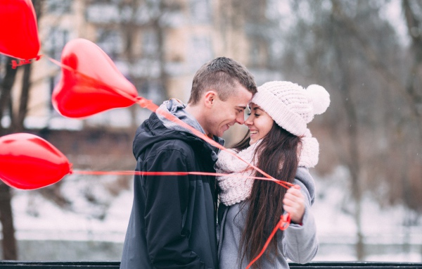 Влюбленная пара с воздушными шарами на улице зимой