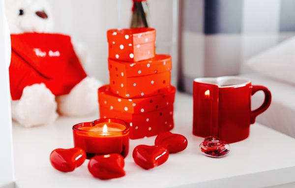 Чашка кофе на столе с подарками, зажженными свечами и сердечками