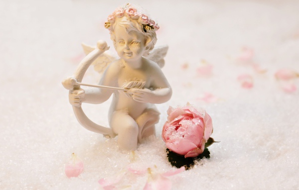 Статуэтка купидона с розой на снегу
