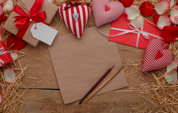 Сердечки из ткани на столе с бумагой и подарками 