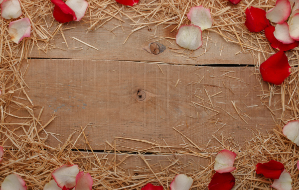 Сено и лепестки роз на деревянном столе 