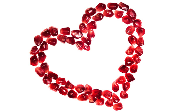 Сердце из гранатовых зерен на белом фоне