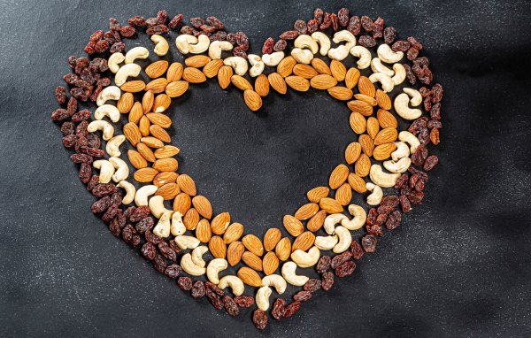 Сердце из орехов и изюма на сером фоне