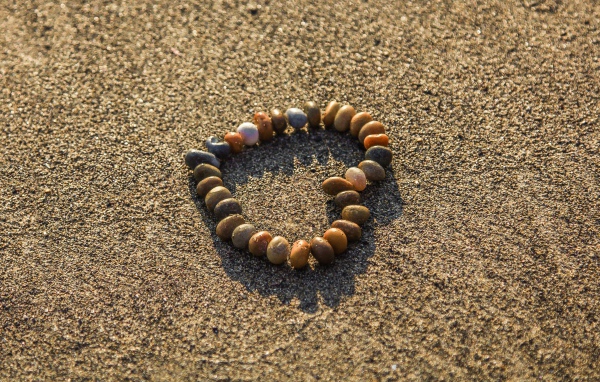 Сердце из мелкий морских камей на песке 