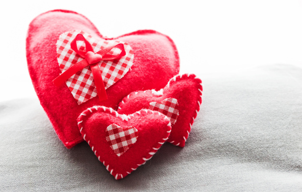 Сердечки из ткани лежат на серой поверхности 