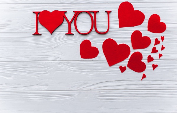 Надпись Я тебя люблю с красными сердечками на столе