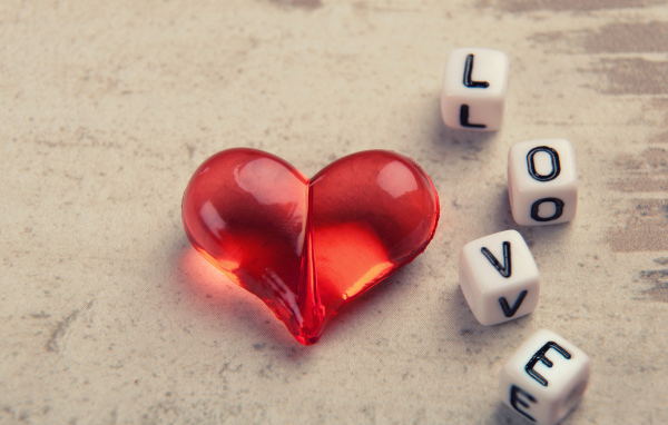 Красное стеклянное сердце на столе с кубиками