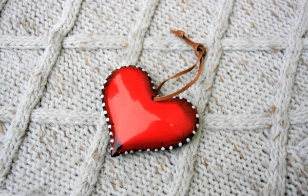 Красное сердце лежит на вязаном свитере 