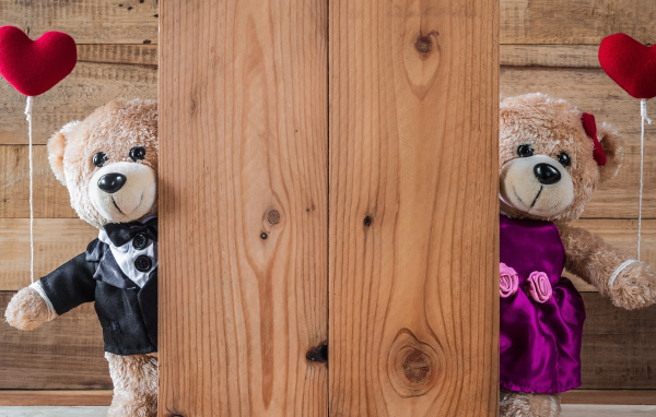 Два плюшевых медведя с сердечками у стены